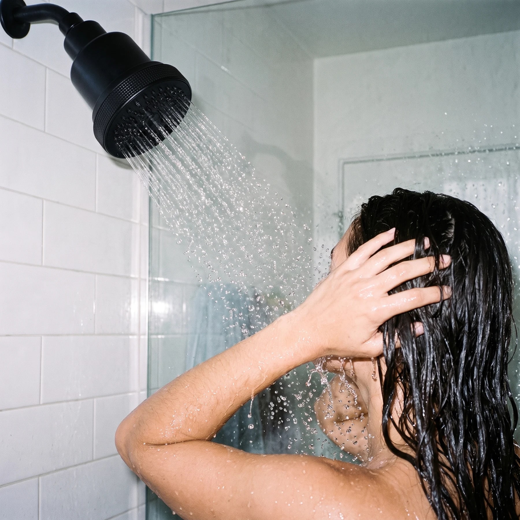 Hair rinsed beneath an installed matte black Clyr showerhead